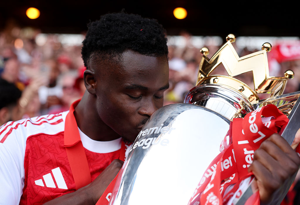 Bukayo Saka of Arsenal kisses the Premier League trophy.