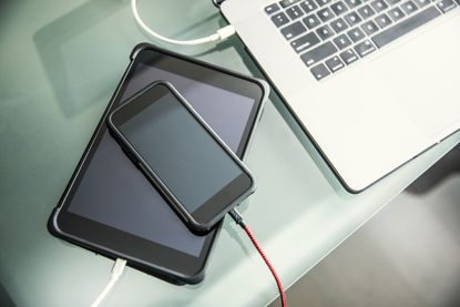 An iphone, ipad, and laptop all charging on a table