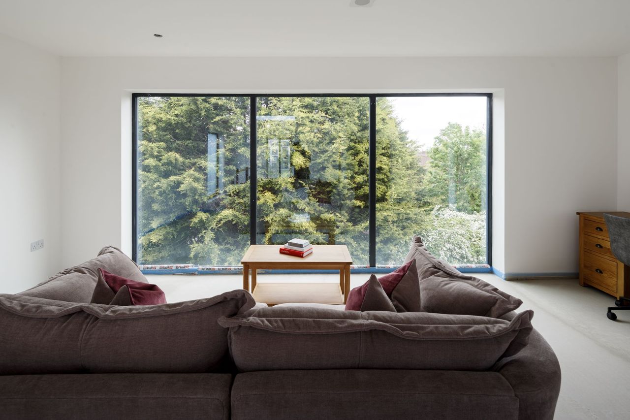 The sofa looks out of the window on the second floor of the home