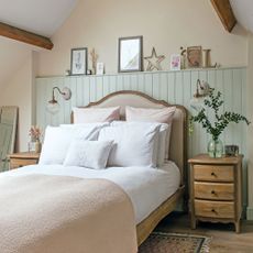 Pastel bedroom with upholstered bed, wood wall panelling, wall lights, exposed beams