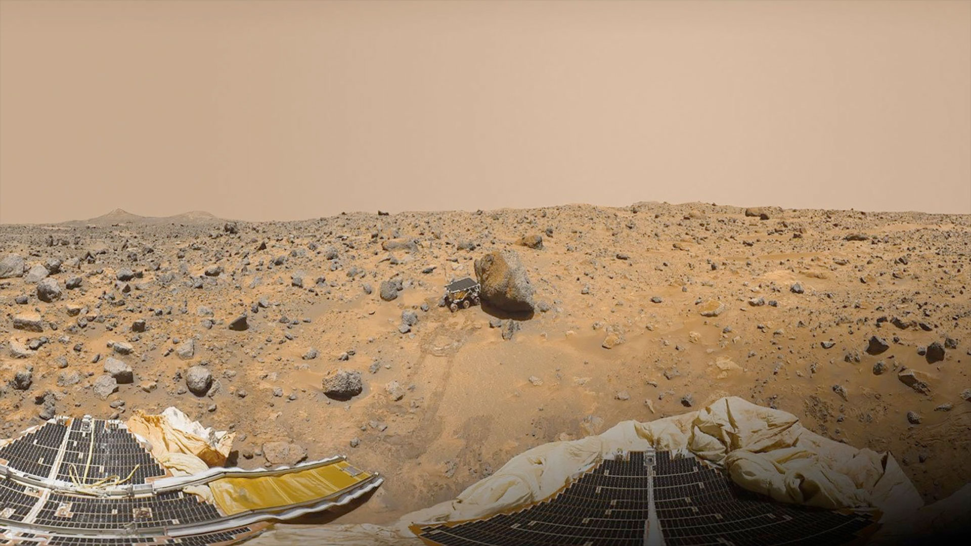 a small rover is seen parked next to a small boulder as tracks lead back to is lander on the planet Mars