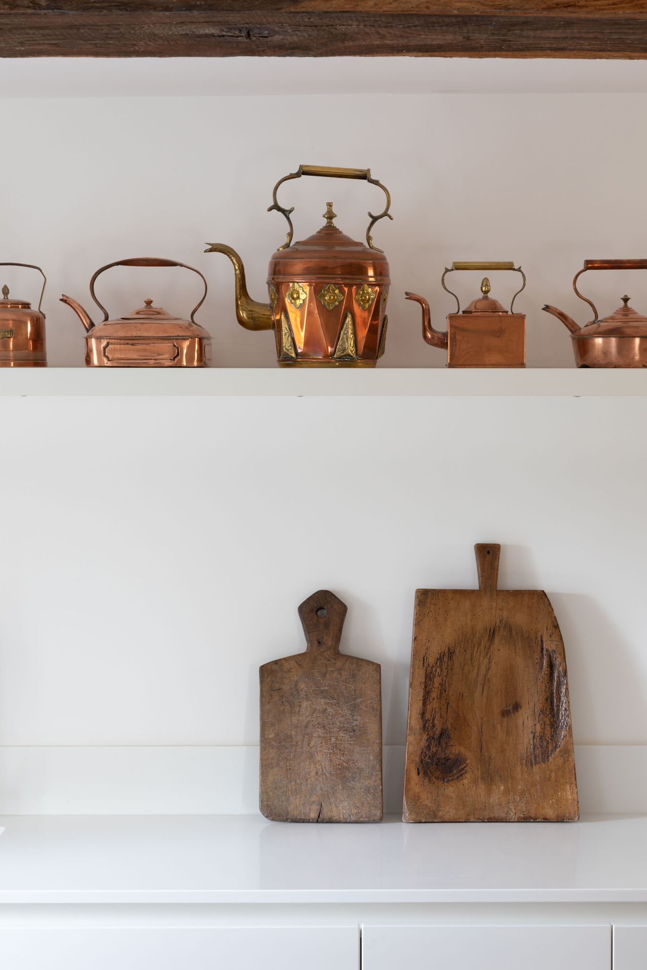 Minimalist white shelf and surface top, chopping boards and brass kettles