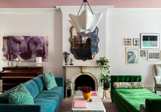 A living room with a teal couch and an emerald green daybed