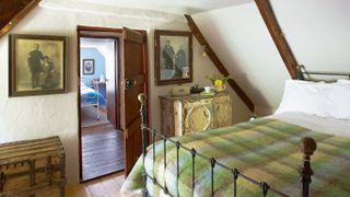 bedroom with tartan bedspread, wooden doors and wooden beams