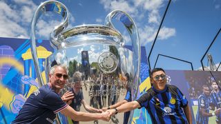 An Inter and a PSG fan posing with a giant trophy ahead of the 2025 Champions League final in Munich, Germany on May 29, 2025.