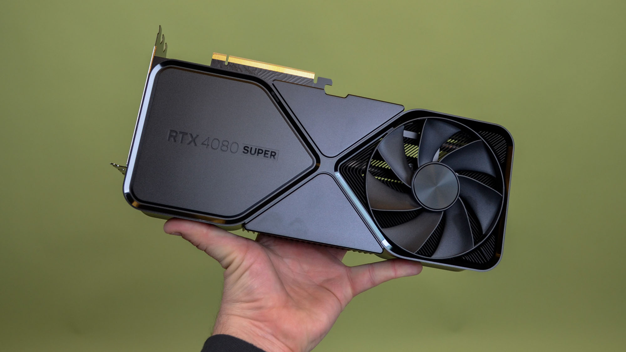 A masculine hand holding the Nvidia GeForce RTX 4080 Super
