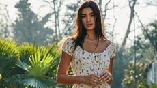 Woman wearing a white Urban Outfitters dress with trees in background