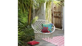 La Redoute Reelak Hammock Chair in a grey courtyard with a wooden door and plants