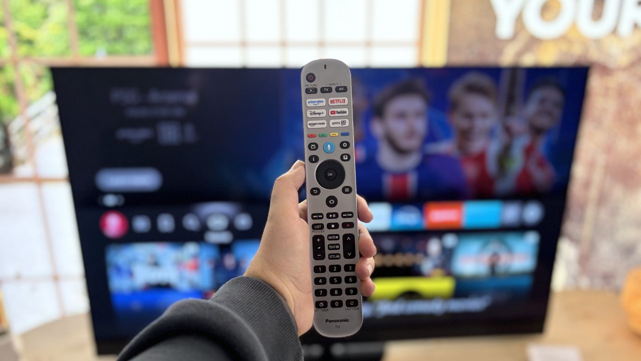 The Panasonic Z90B 48-inch OLED TV's remote control held in front of the TV.
