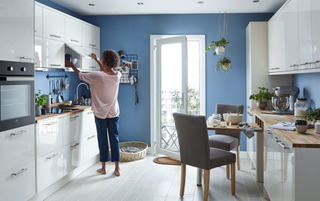 A galley kitchen with white cabinets, blue walls and dining table
