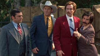 From left to right: Steve Carell looking confused, David Koechner looking concerned while wearing a cowboy hat, Will Ferrell looking forward and Paul Rudd making a finger gun with his right hand.