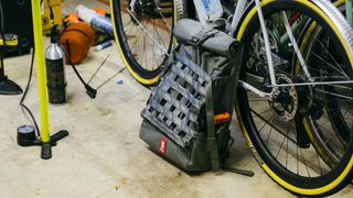 A grey Chrome Industries backpack leans on a white gravel bike in a garage