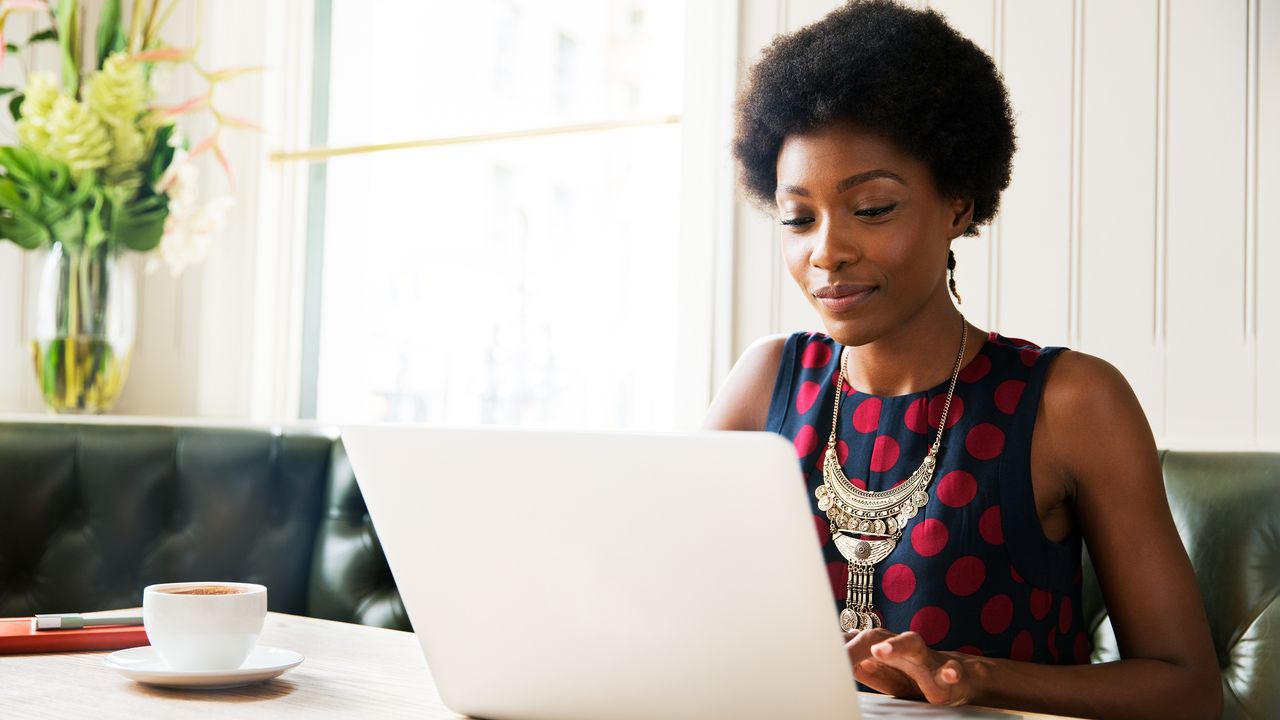 A woman works on her laptop at her dining room table.