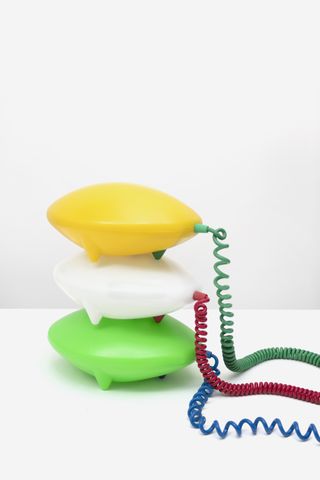 Three plastic table lamps in yellow, white and green by IKEA, featuring curly cords in green, red and blue
