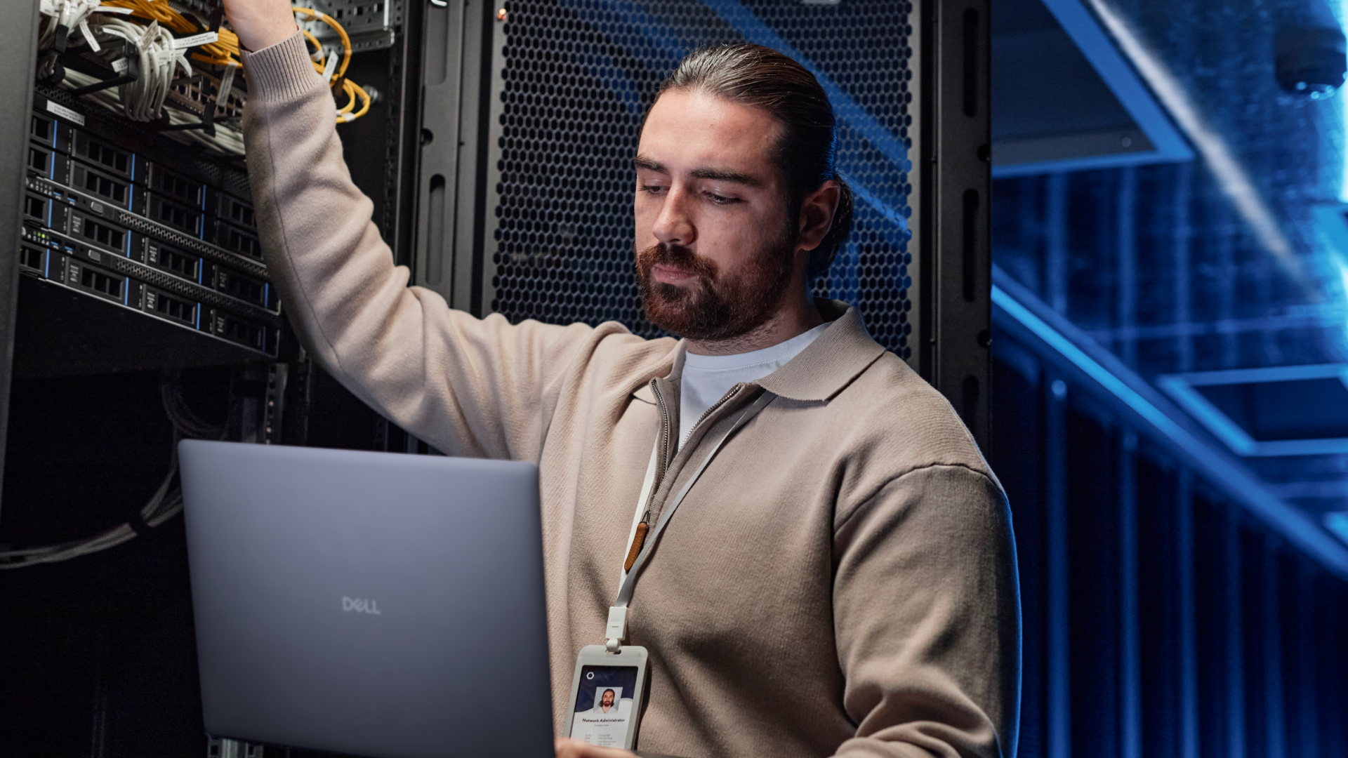 Person working on a laptop next to a server in a data center