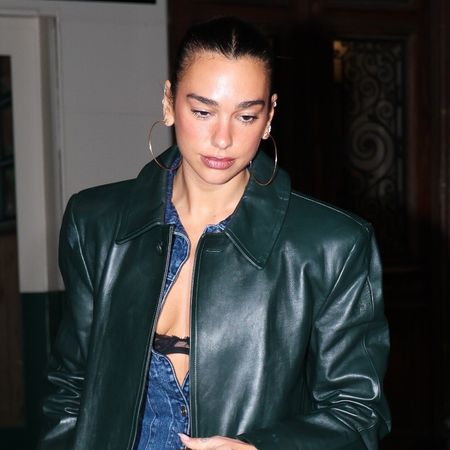 Dua Lipa wearing a long green leather coat, denim jumpsuit, kelly green Chanel 25 bag, and furry brown boots
