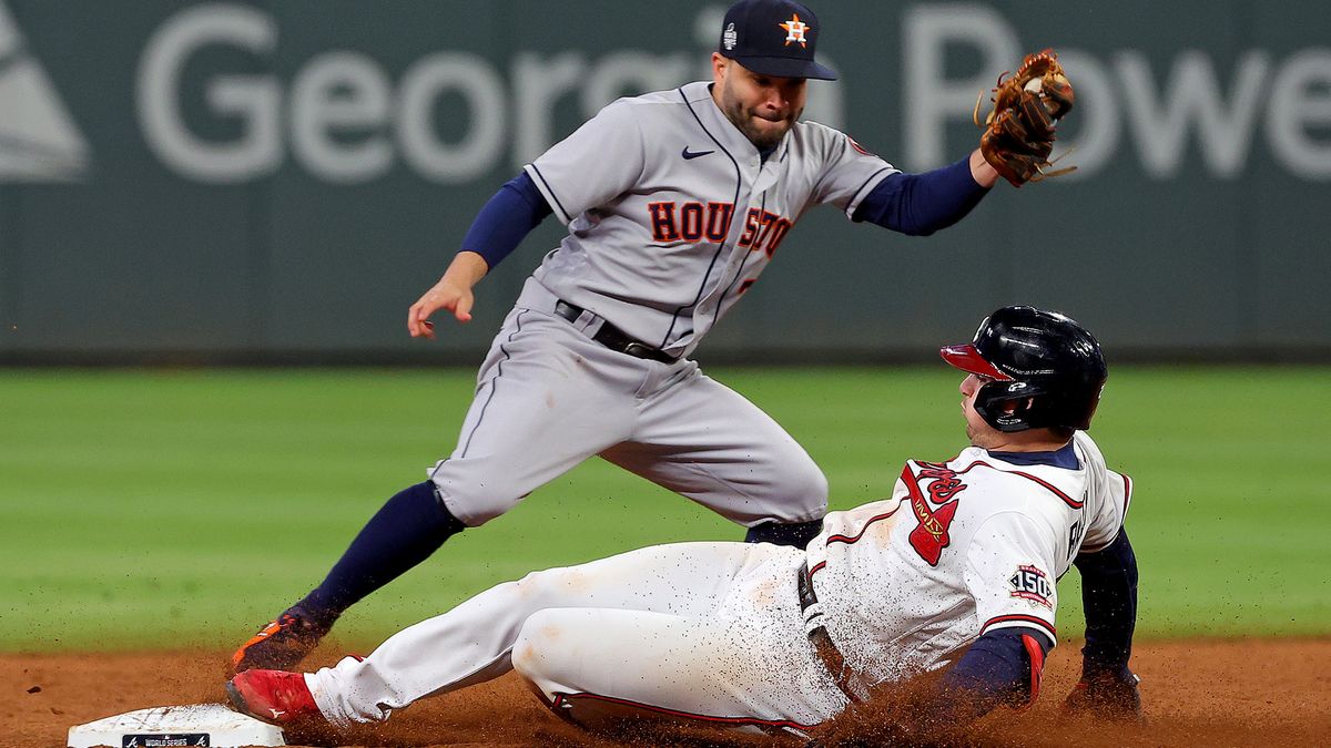 Austin Riley #27 of the Atlanta Braves slides in safely under the tag of Jose Altuve #27 of the Houston Astros at second base after advancing on the throw after hitting an RBI single during the sixth inning in Game Four of the World Series at Truist Park on October 30, 2021 in Atlanta, Georgia.