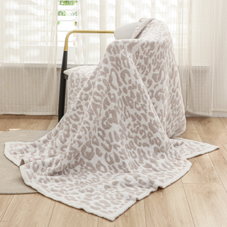 A beige and white leopard print throw blanket draped over a chair