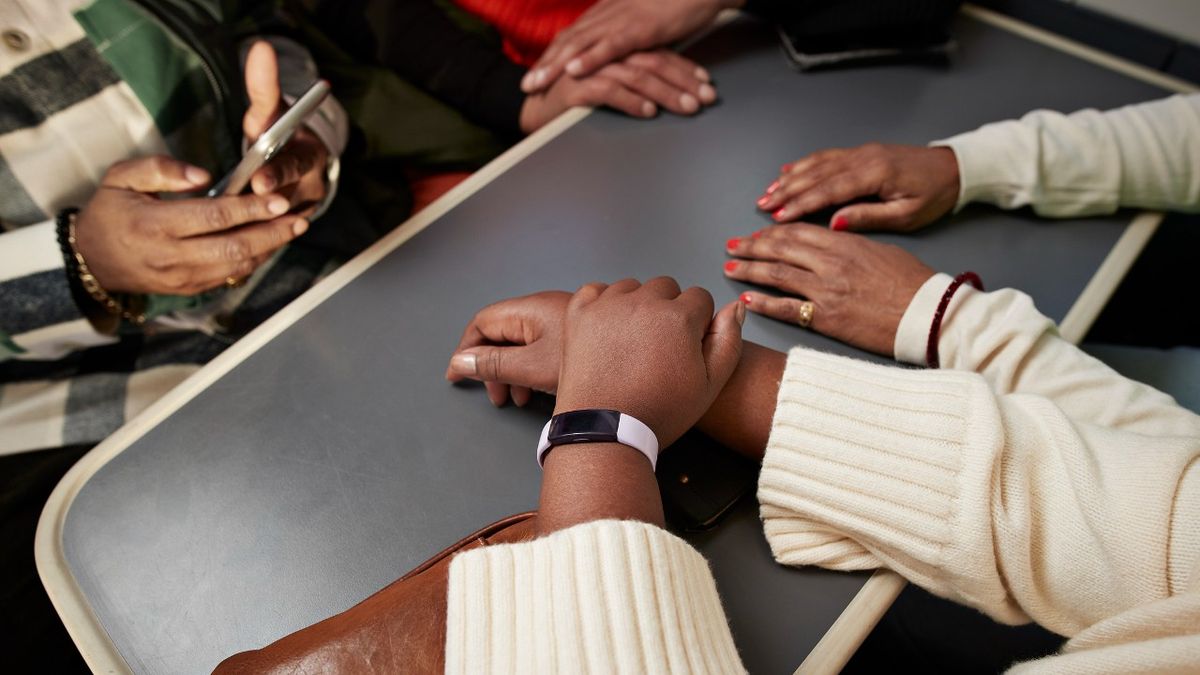 Hands on a table, one person is wearing a fitness tracker