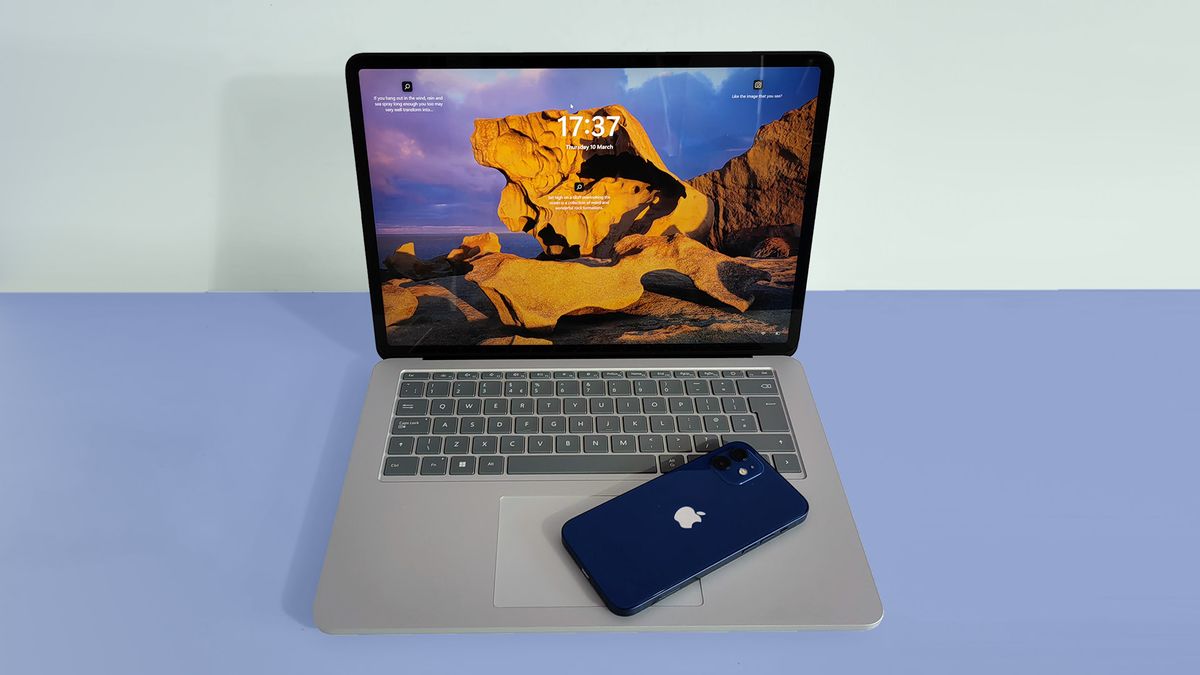 A MacBook with a phone resting on the keyboard