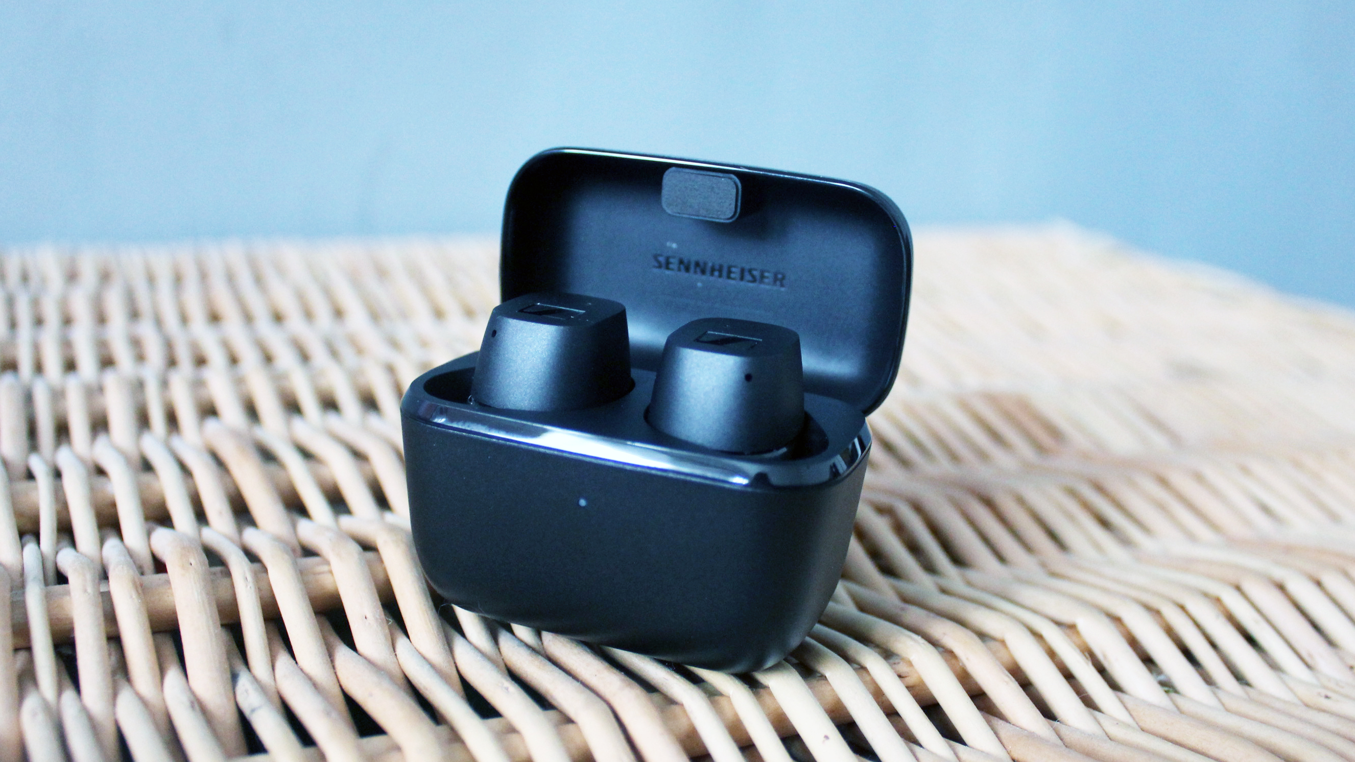 the sennheiser cx true wireless earbuds in their charging case on a wicker background