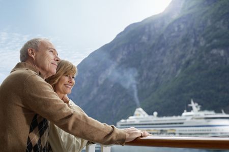 A mature couple on a deck of a cruise ship with another cruise ship in the background.
