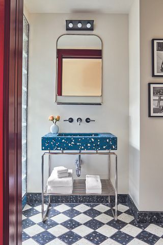 A contemporary hotel bathroom designed by Ash NYC with bright blue terrazzo sink and grey and white chequerboard floor tiles