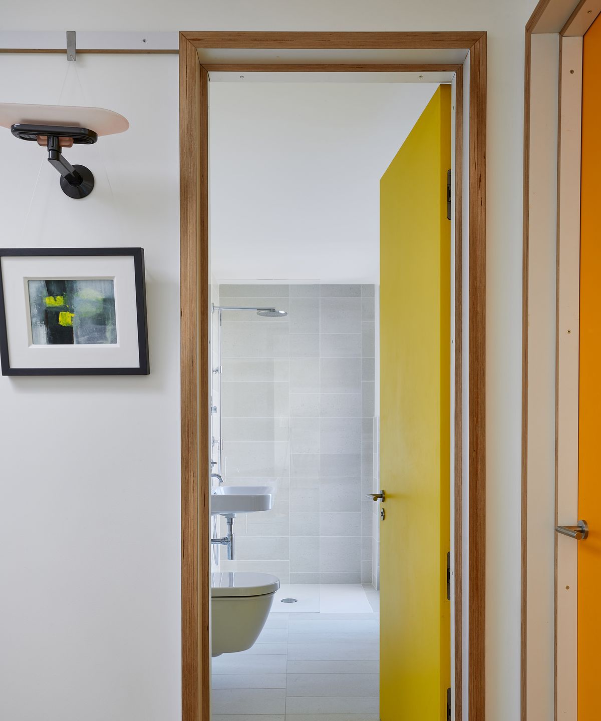 A bright yellow door with timber door frame opening into a bathroom