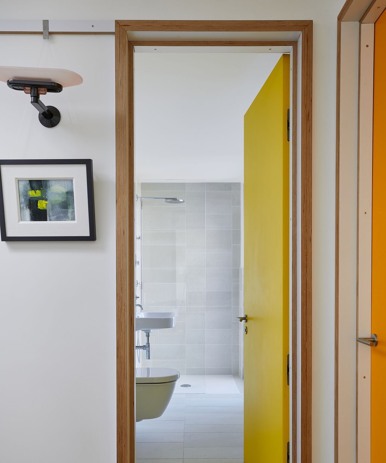 A bright yellow door with timber door frame opening into a bathroom