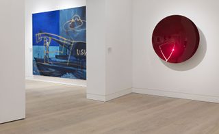 A blue modern painting is hung on the wall to the left. A red spherical, reflective art piece is set to the right.