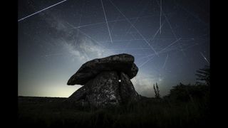 Satellites are pictured leaving long 'trails' in the night sky in a composite image featuring the Milky Way hanging over a stone monument.