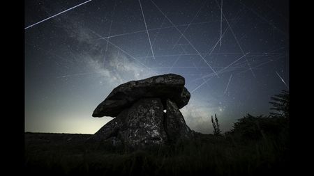 Satellites are pictured leaving long 'trails' in the night sky in a composite image featuring the Milky Way hanging over a stone monument.