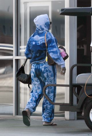 Rihanna walks into an airport wearing a sweatsuit with three designer bags