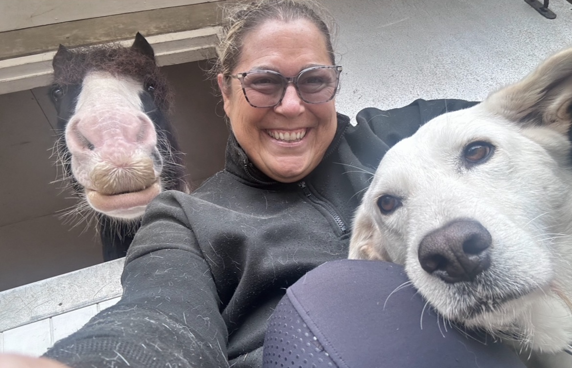Sally smiling with her piebald horse Dexter and retriever Pedro