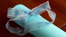 Rolled up yoga mat with ribbon tied around it on wooden floor