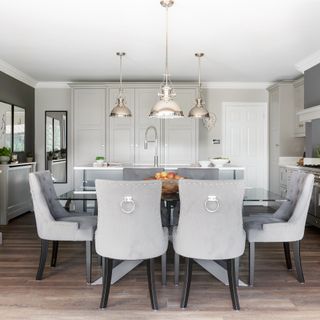 A modern kitchen with glass dining table and grey dining chair decor