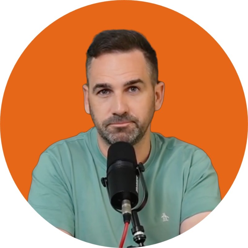 A circular cropped headshot of a man with short hair and a beard wearing a teal t-shirt, seated at a podcast microphone against an orange background.