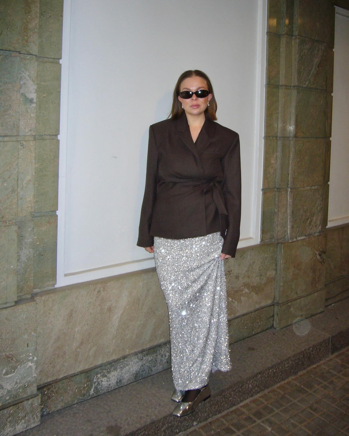 Dina wears a brown blazer, silver sequin skirt, and silver wedges.