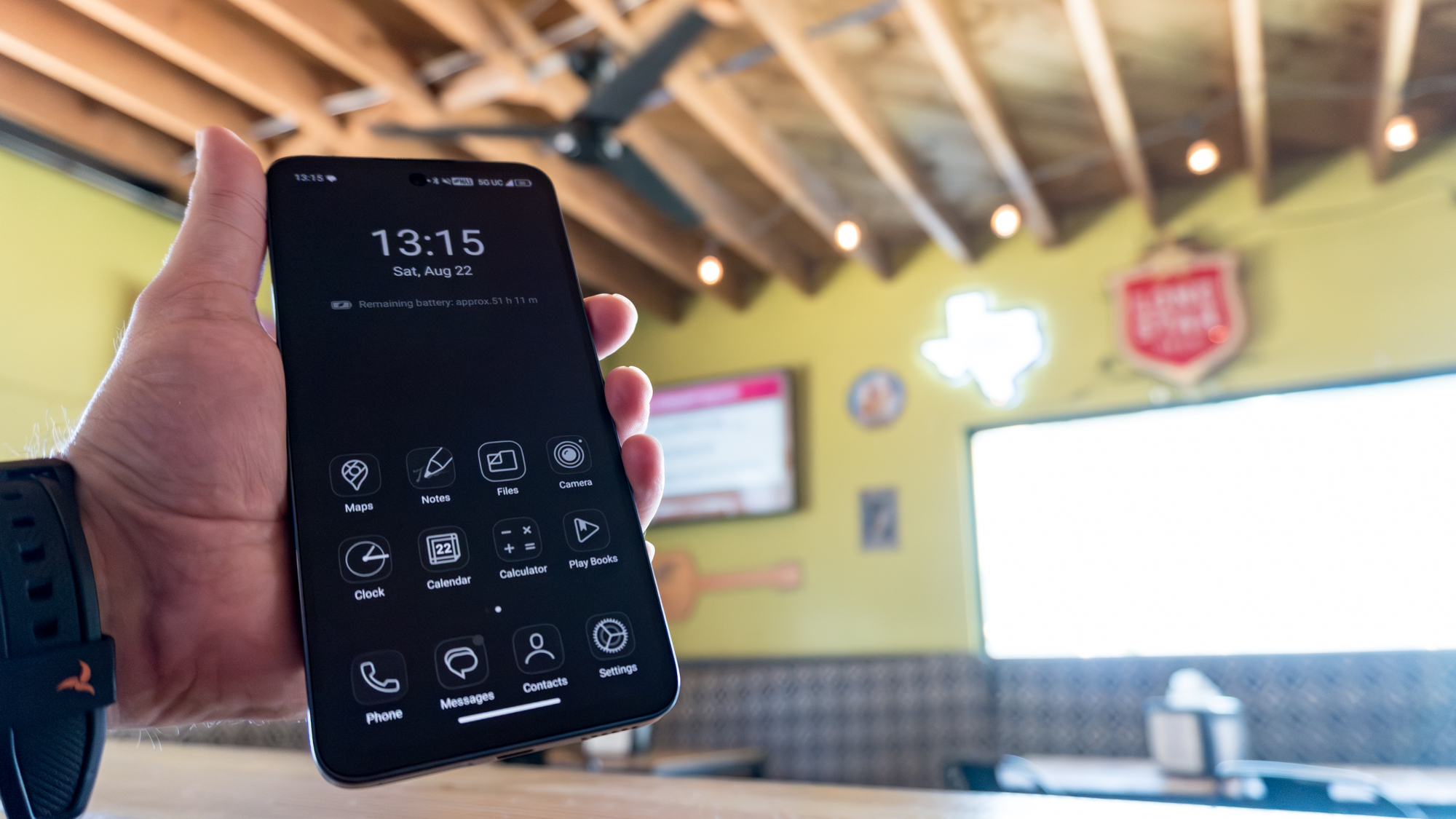 A person holding up the TCL NXTPAPER 70 Pro with the device in Max Ink Mode at a restaurant
