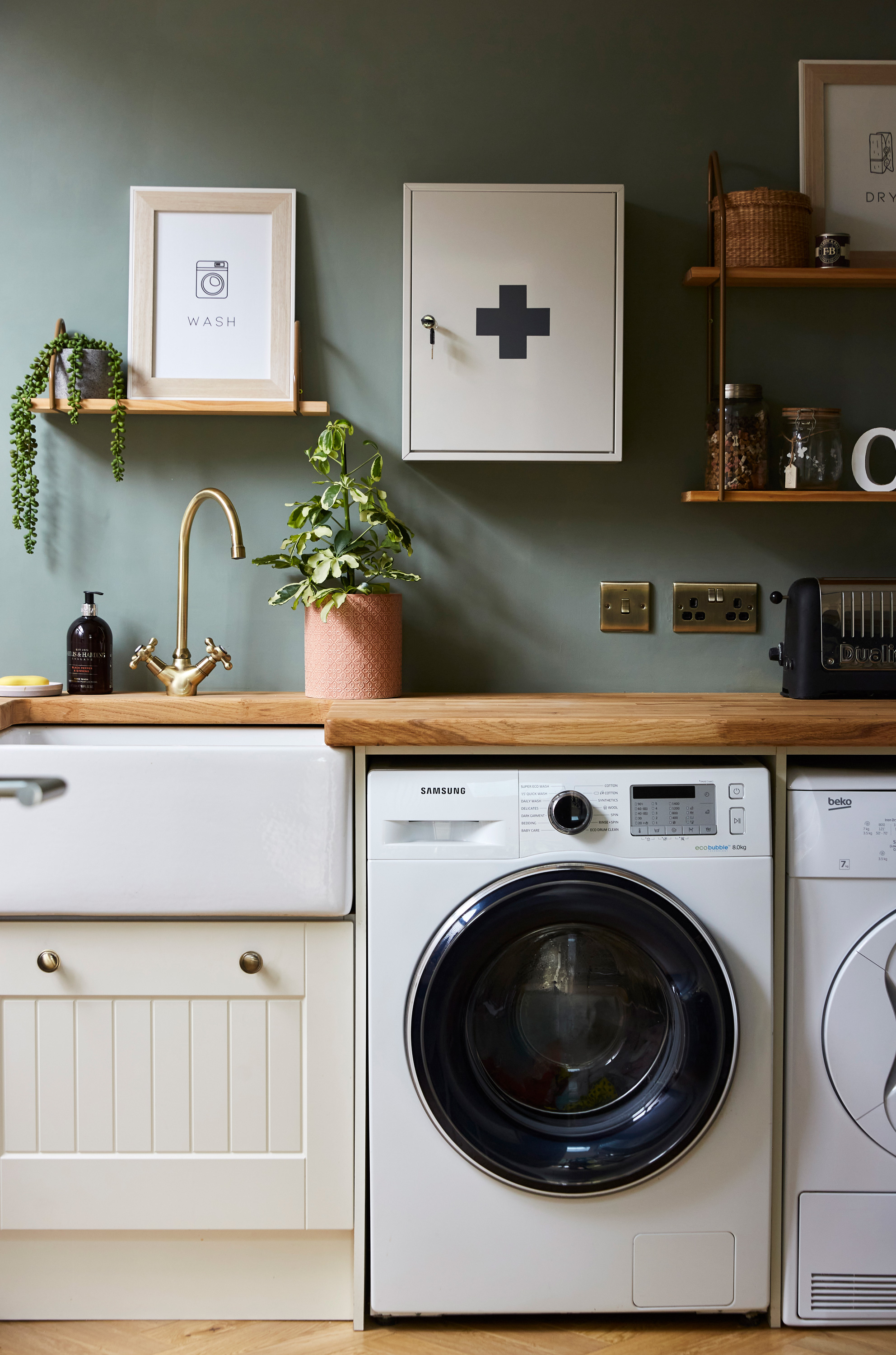 A laundry utility room with green wall paint decor and white washing machine