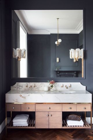 A small bathroom with sculptural sconces and gold toned pendant light