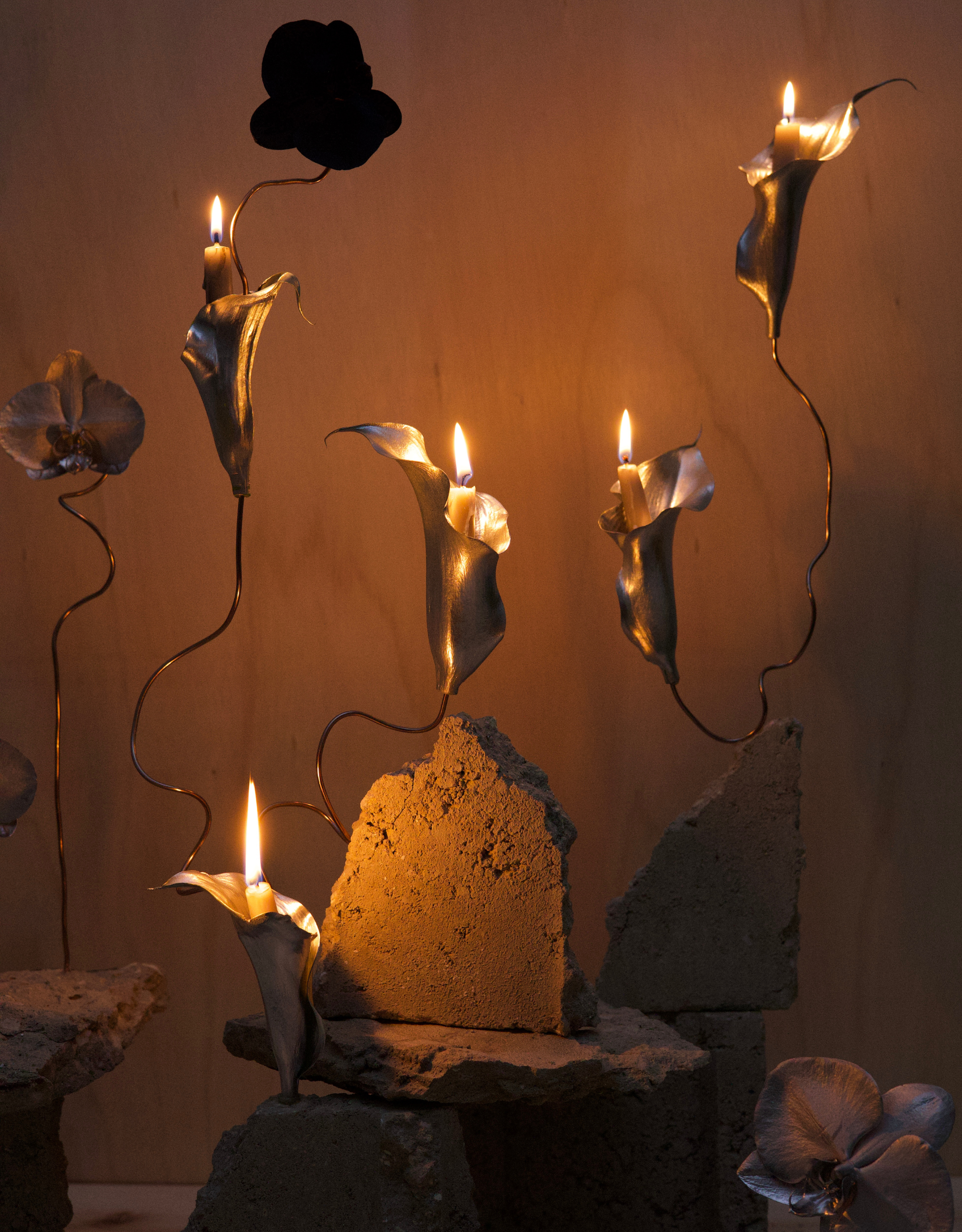 An artistic installation with metal sculpted calla lilies with mini candles woven into concrete blocks