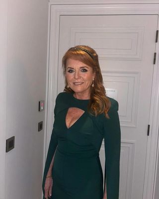 Sarah Ferguson wearing a green evening gown standing in front of a white door