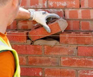 bricklayer placing brick on outer skin of wall
