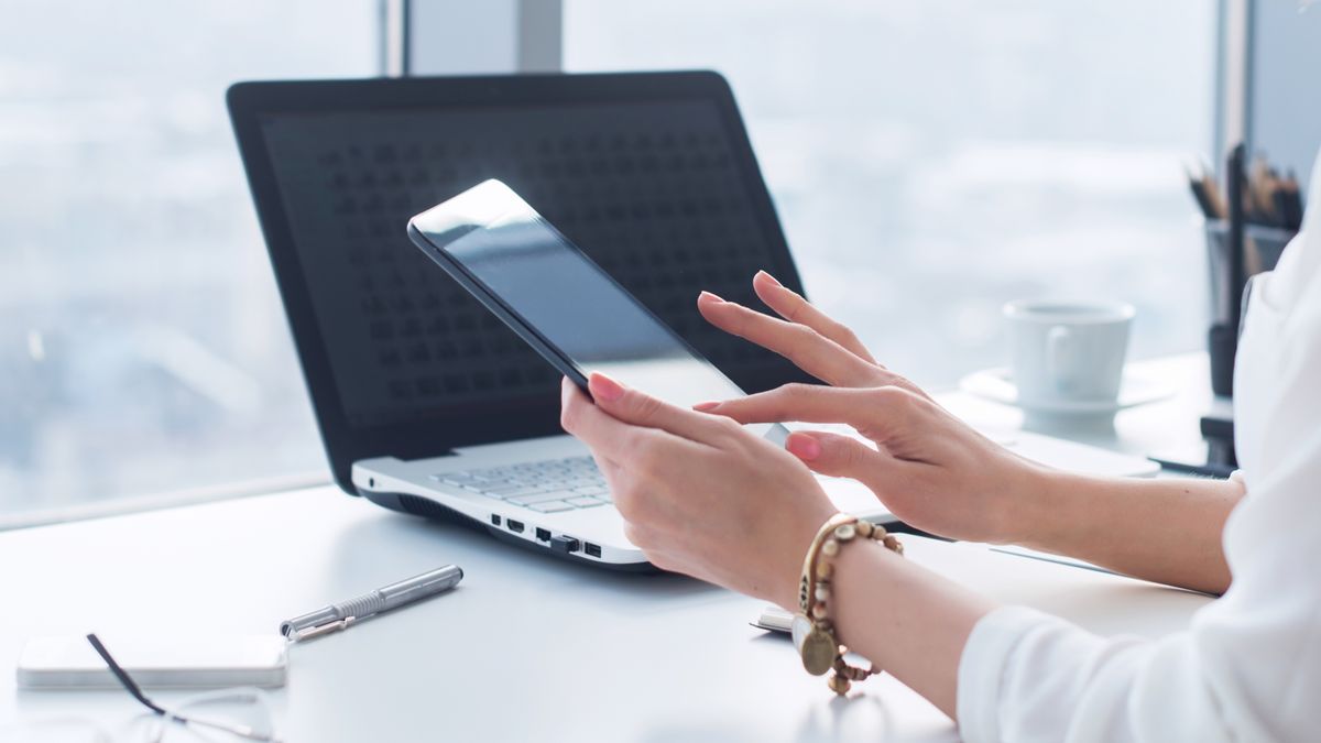 An employee checking their smartphone at work, using a personal device for work purposes