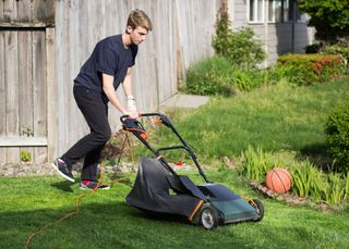 teenage boy mowing a lawn
