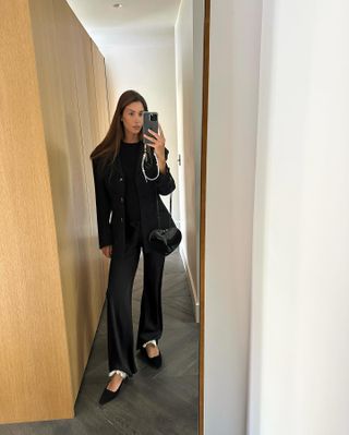 @jaimeridge wears a black blazer with matching satin wide-leg trousers.