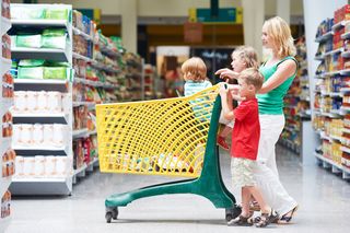 A woman and children walk with a shopping cart