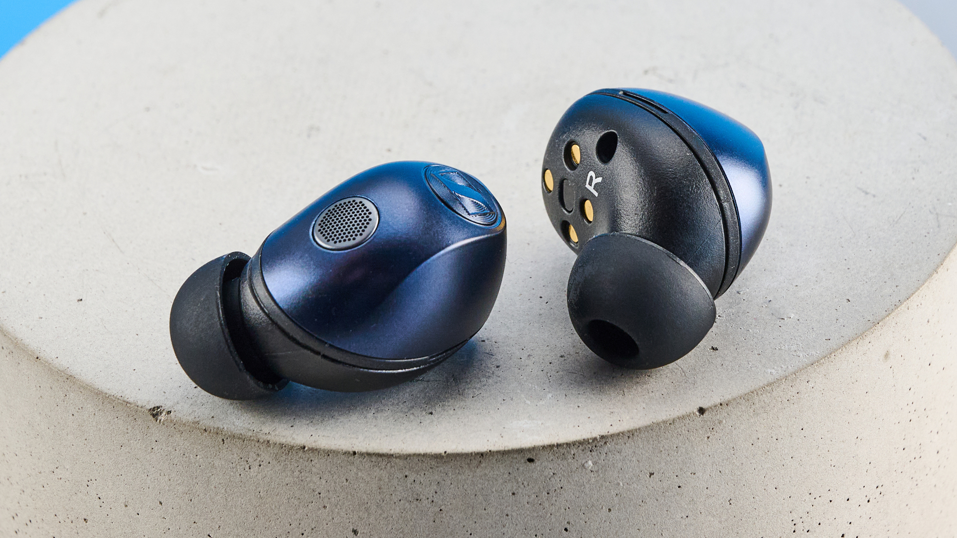 the sennheiser momentum 5 true wireless earbuds in navy photographed with the blue tom's guide background