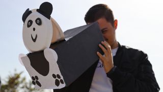 a man looks through a pinhole projector that has been decorated to look like a panda.